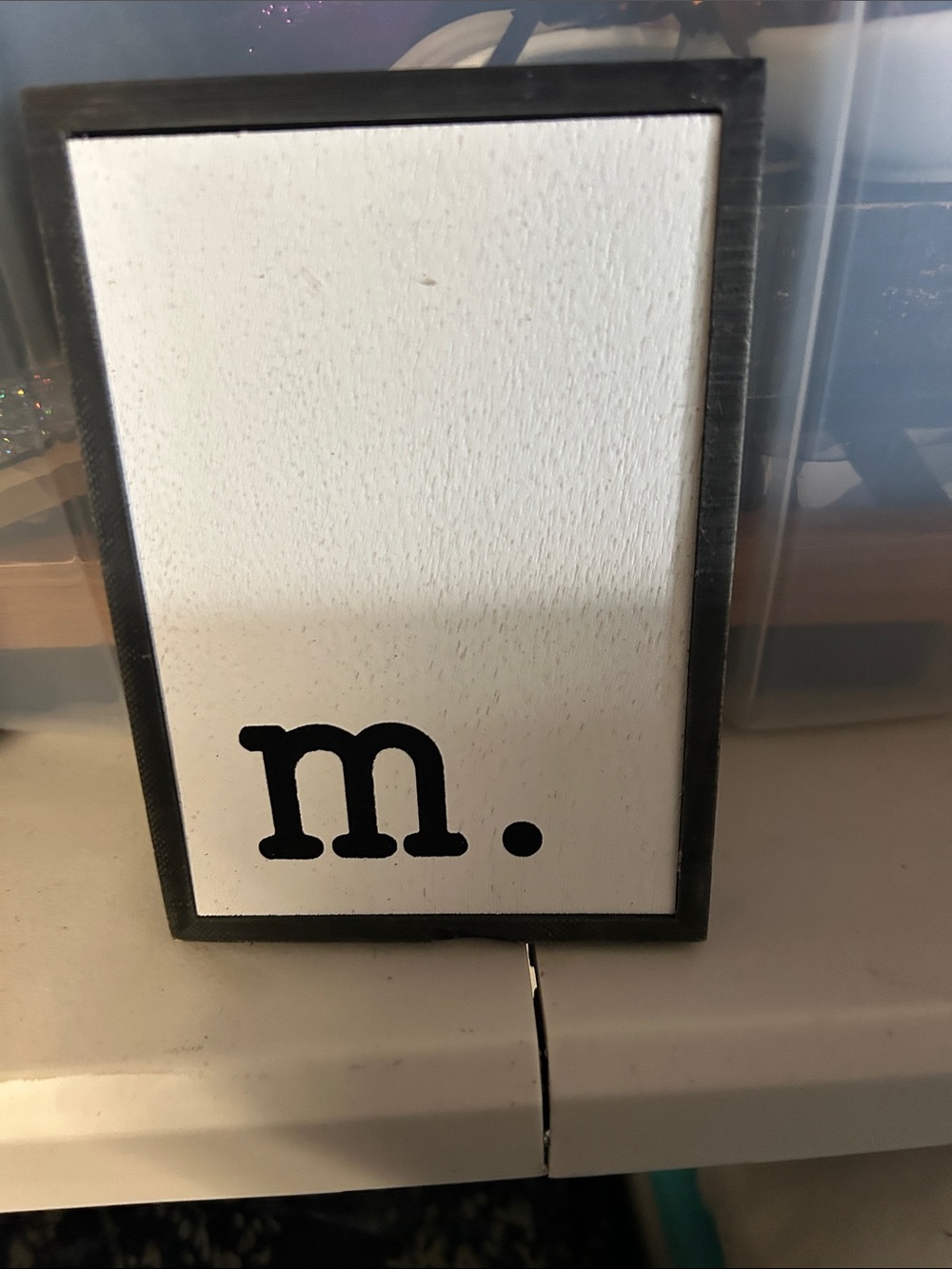White Framed Wood Wall Art with Black 'm.' Accent